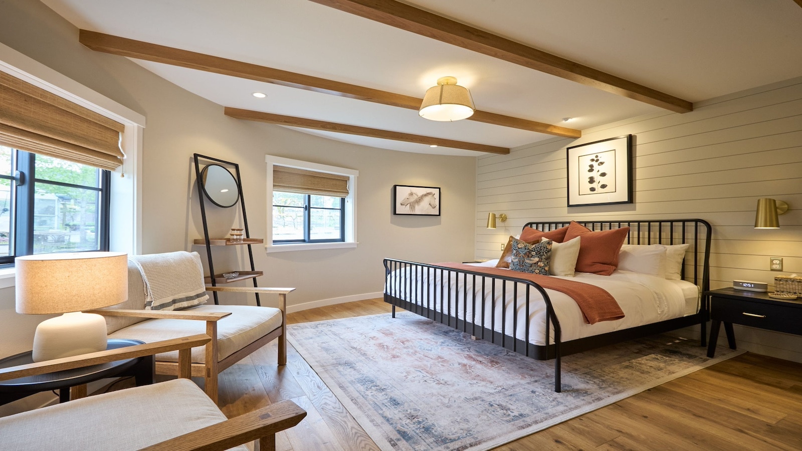 Chardonnay suite with beige walls, wood floors with carpet, wrought iron headboard, multicolored bedding and sitting area